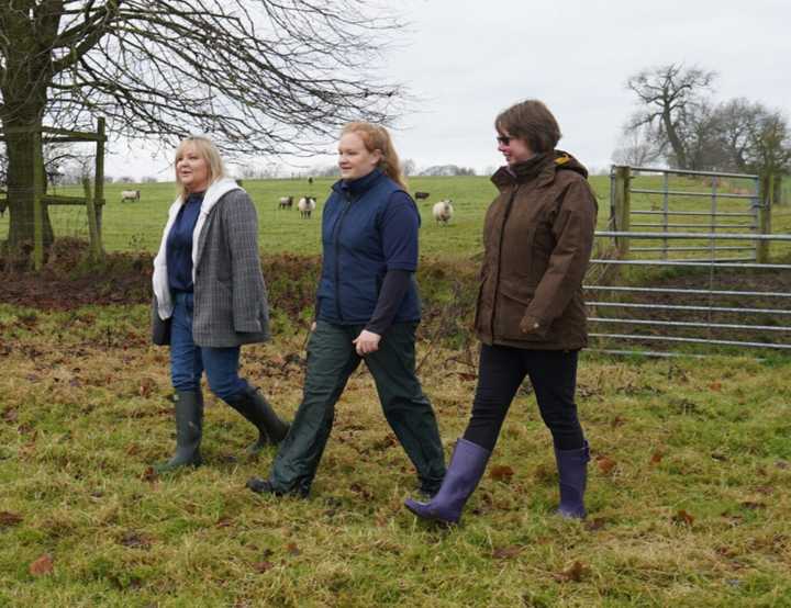 Female vet with two ladies walking across a field
